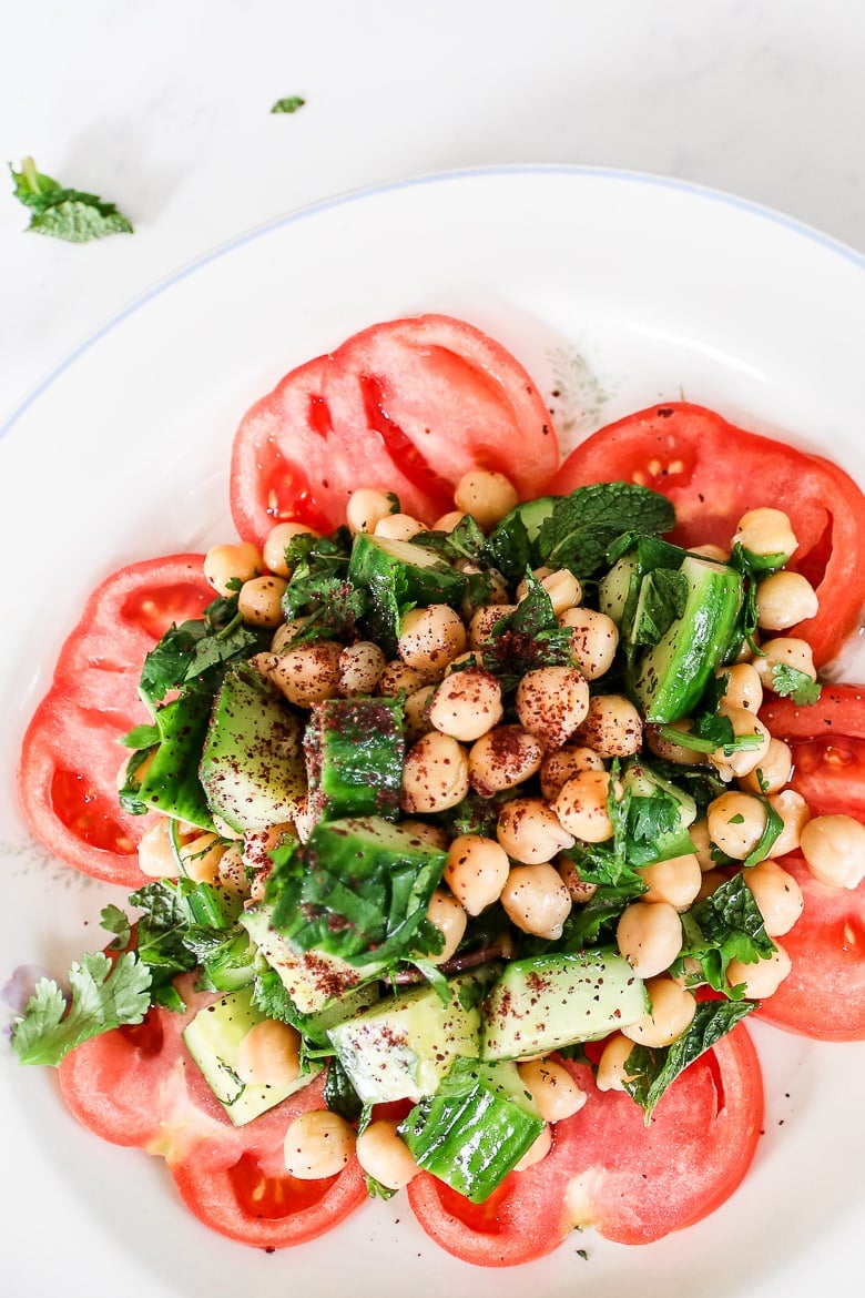 plate of chickpea herb salad on a bed of sliced tomatoes