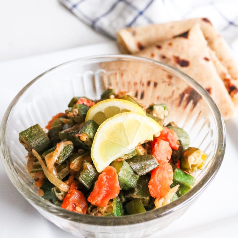 pkra (bhindi) in a bowl with roti and lemon slices