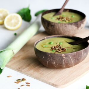 mint and pea soup served in 2 coconut bowls with leek and lemon on the side