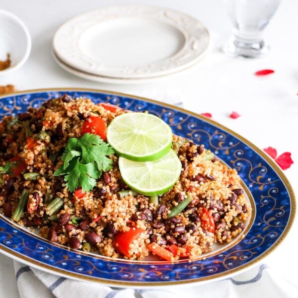 plate of quinoa pilau with tomato, water and empty plates and forks on the side