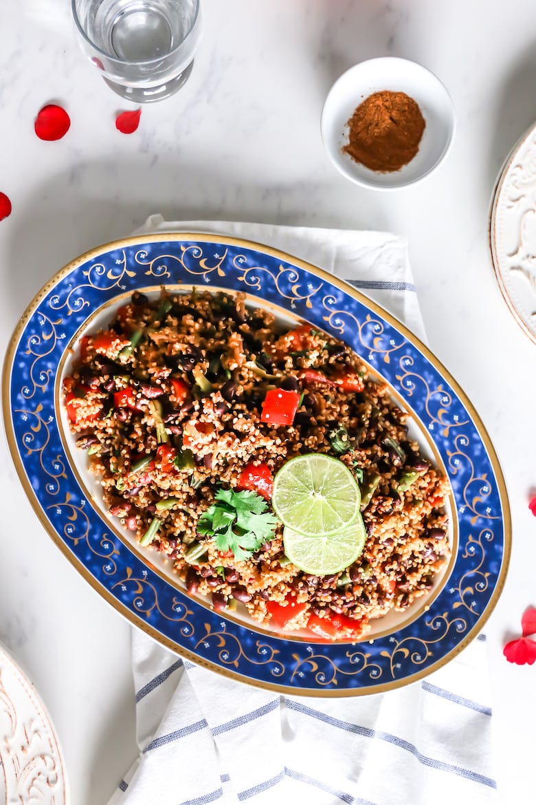 plate of quinoa pilau with tomato, water and empty plates and forks on the side