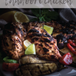 grilled tandoori chicken served with grilled vegetables and lime slices.