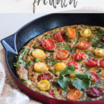 Asparagus Frittata topped with colorful tomatoes in a red pan on a table cloth