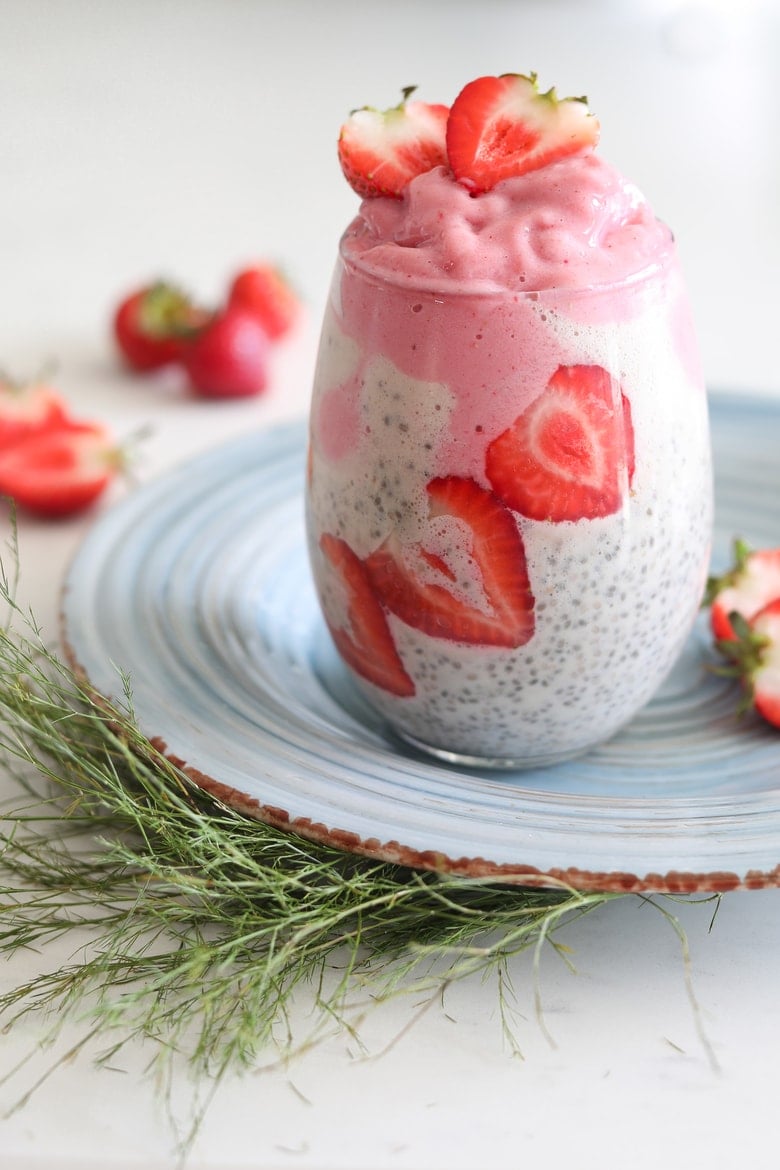 vegan chia pudding in a glass topped with strawberry nice cream and fresh strawberries
