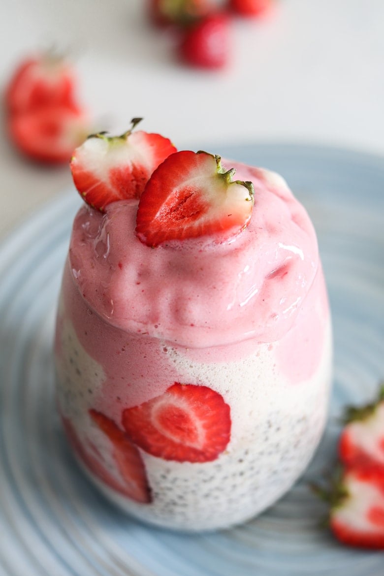 vegan chia pudding in a glass topped with strawberry nice cream and fresh strawberries