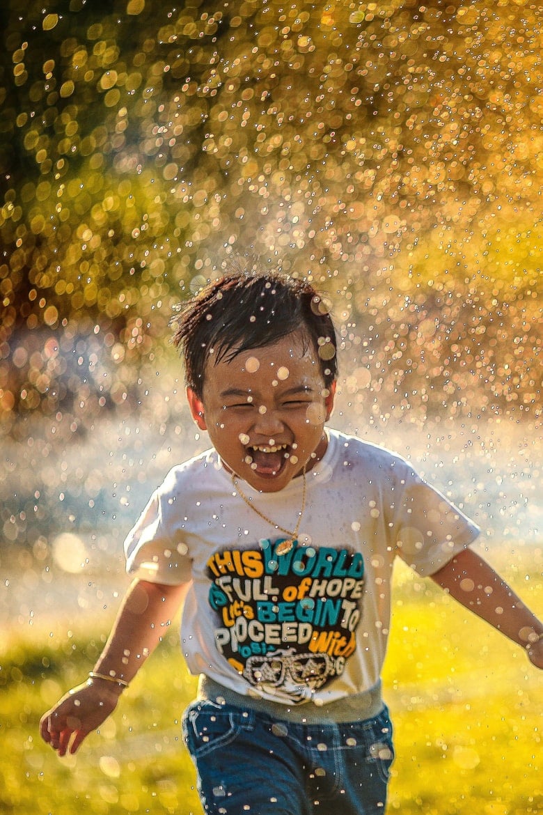 a happy child running in a splash of water on a sunny day