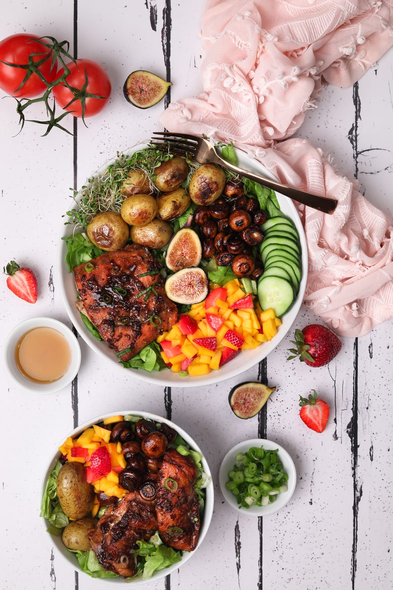Colorful bowl of soy maple glazed salmon fillet served with potatoes, mushrooms, mango and strawberry salad on a bed of lettuce