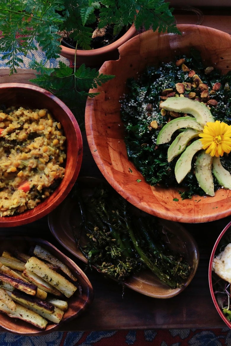 bowls and plates of food with avocado slices, lentils and a green plant