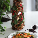 Plate of easy and healthy roasted Brussel sprouts recipe with sweet potatoes and cranberries with a Christmas tree in the background
