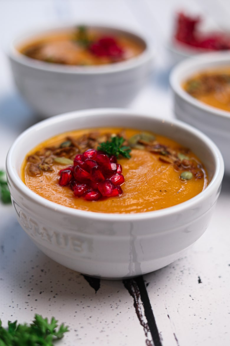 three bowls of tomato soup topped with pomegranate kernels and seeds