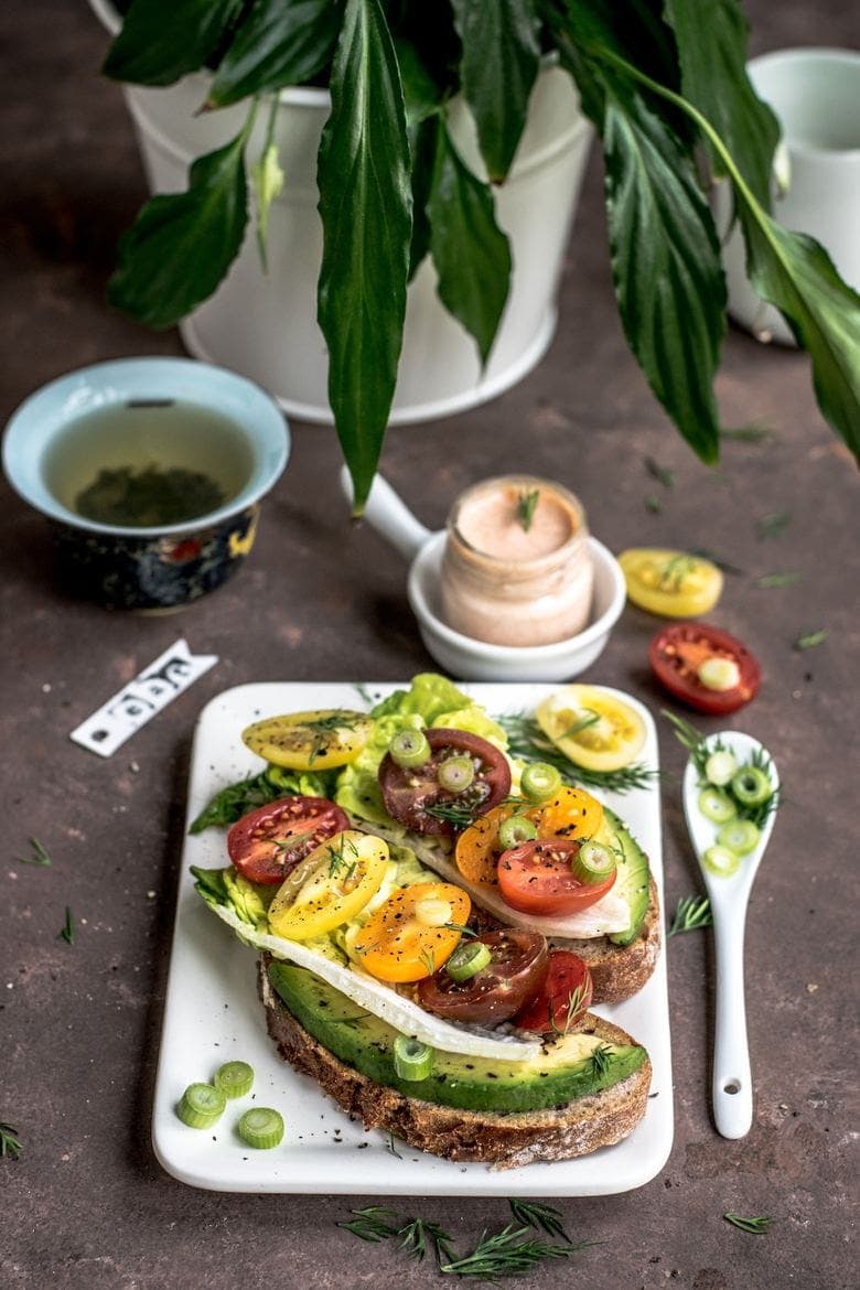 two slices of toast topped with avocado, tomatoes and onion