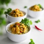 three bowls of coconut shrimp curry on a bed of basmati rice garnished with fresh cilantro leaves