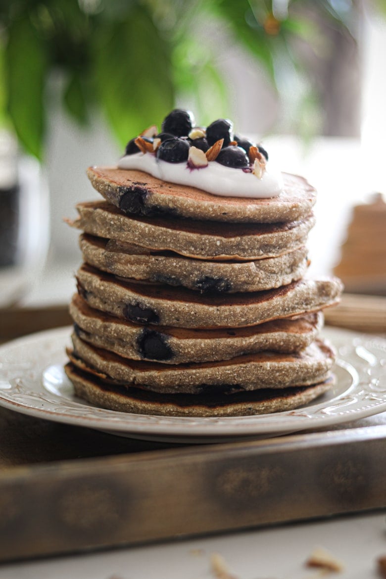 a stack of easy and healthy pancakes in a tray topped with yogurt and blueberries