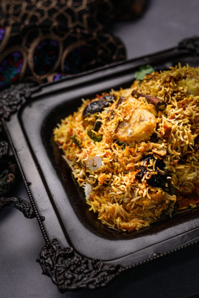 tray of south asian fish biryani with a cinnamon stick on top