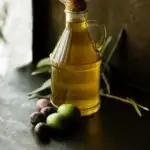 bottle of olive oil with a variety of olives next to it