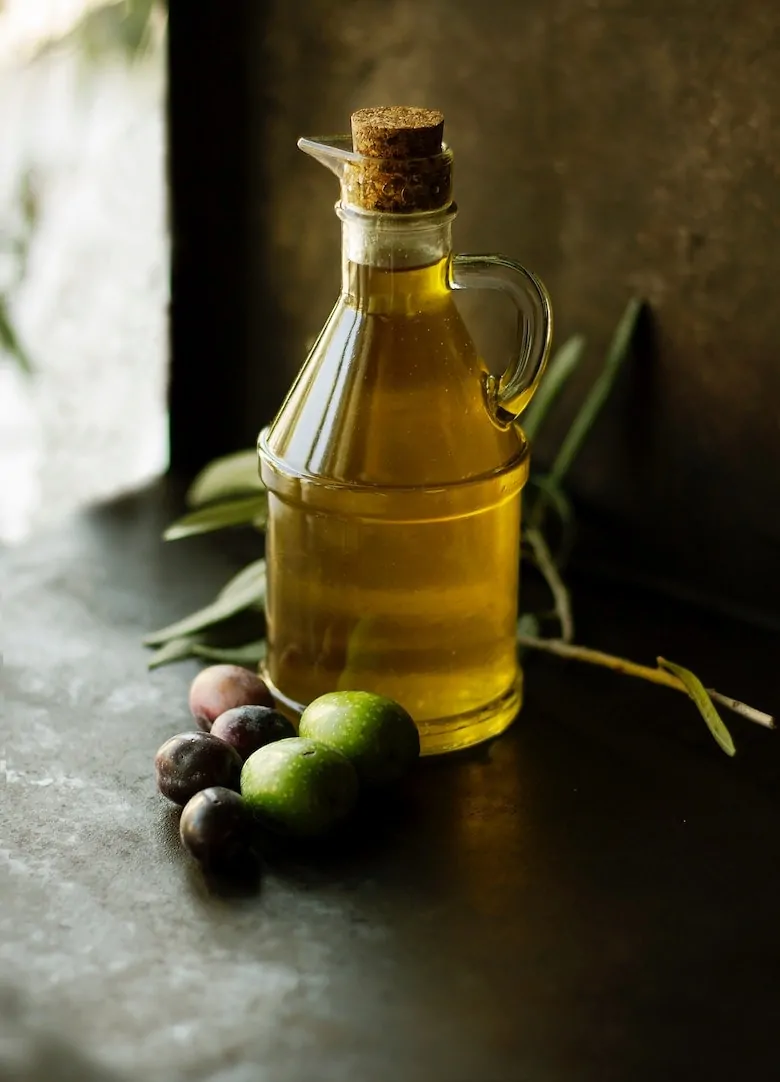 bottle of olive oil with a variety of olives next to it