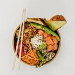 Buddha bowl with salmon and salad with chopsticks resting on top