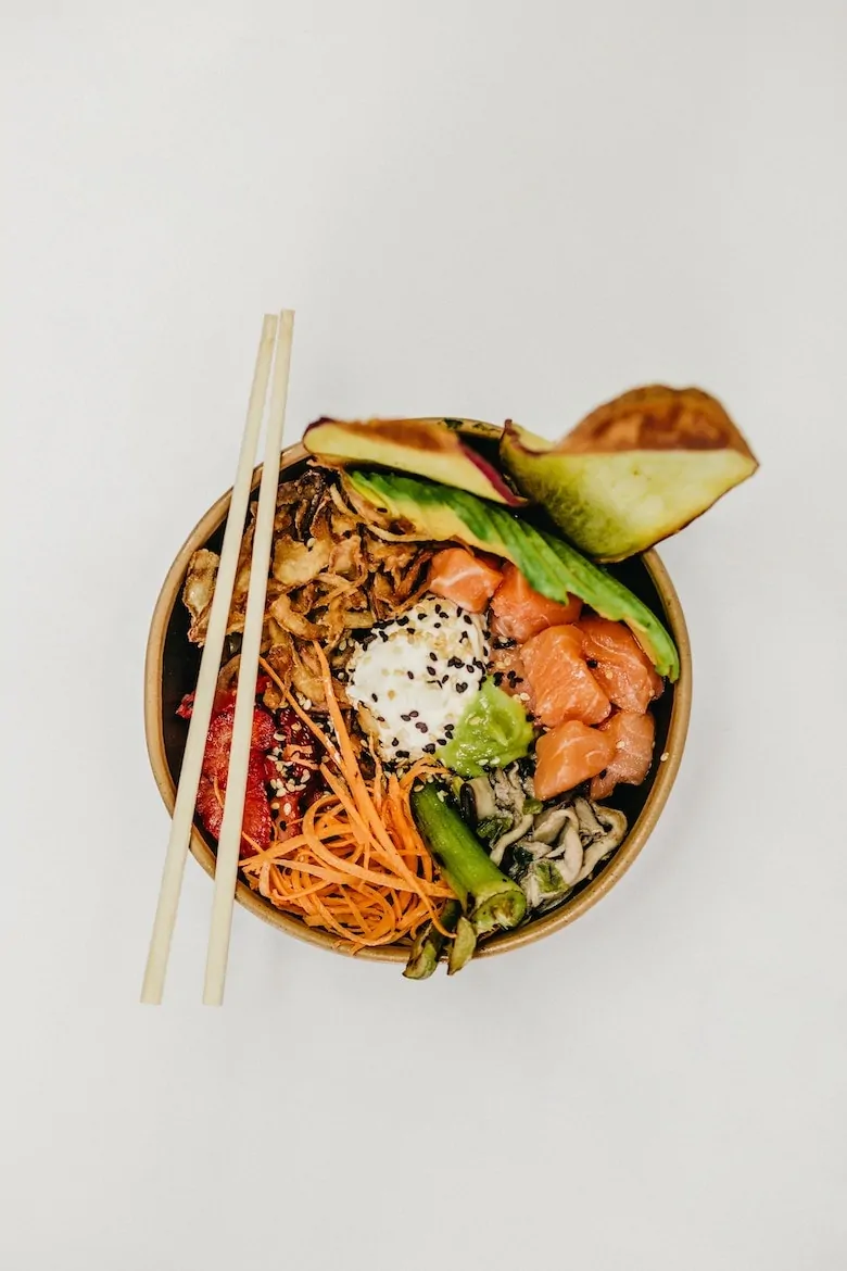 Buddha bowl with salmon and salad with chopsticks resting on top