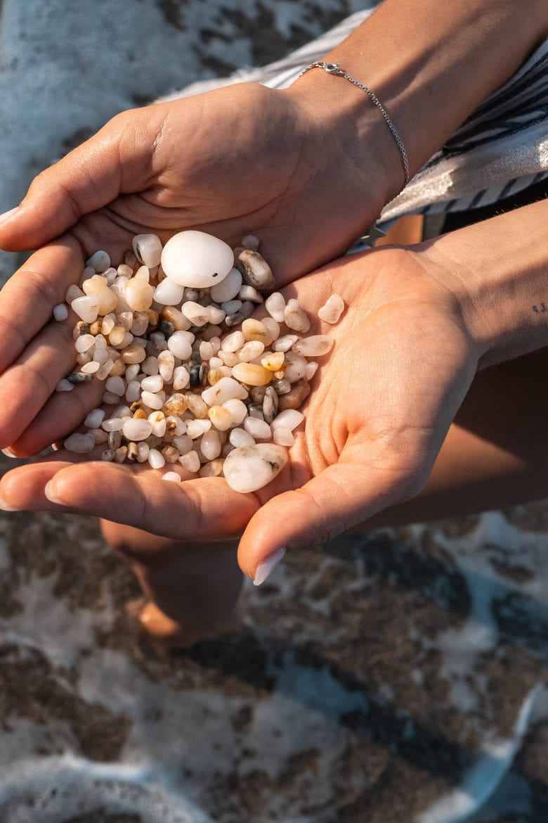 Women's hands are holding a lot of small pebbles of different shapes and sizes