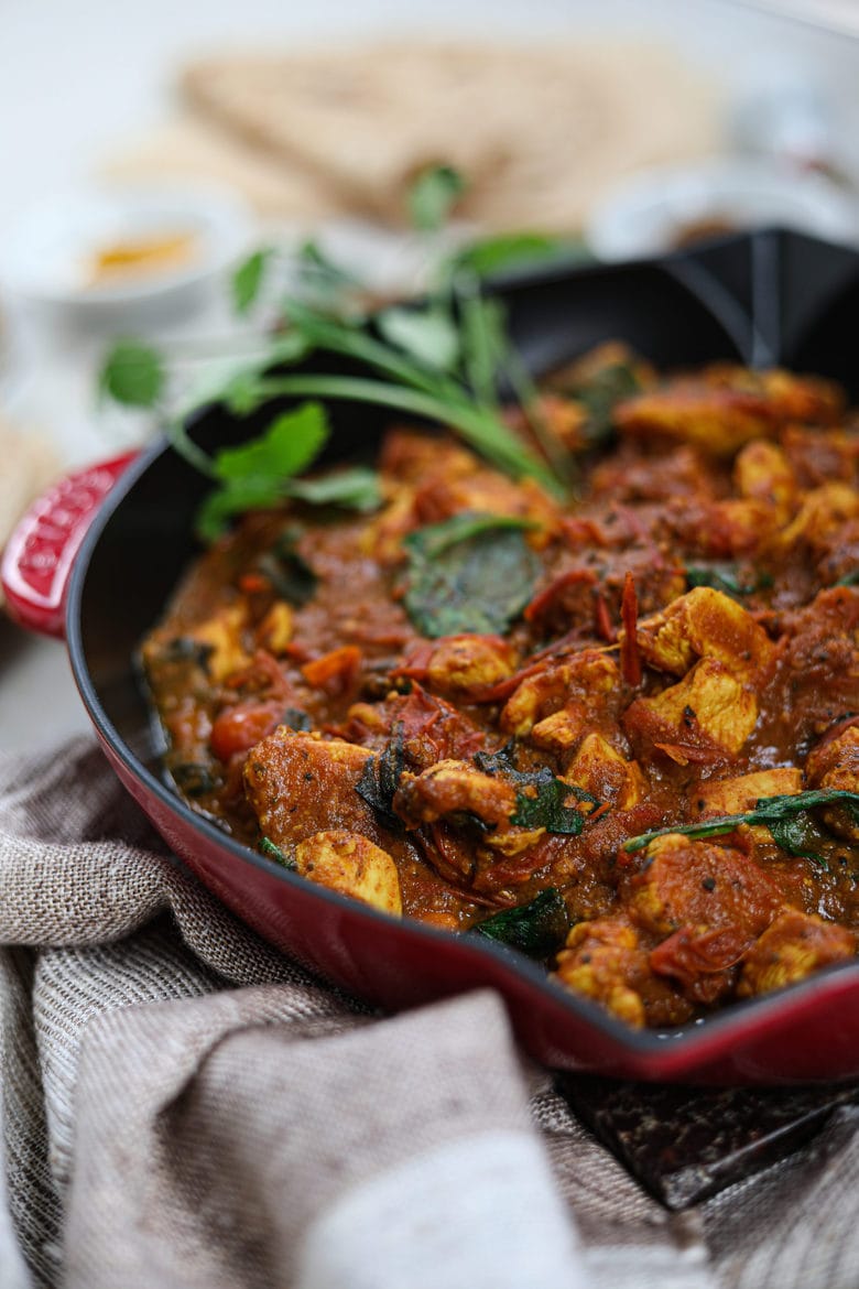 pan of chicken curry made with the best tomato sauce and garnished with fresh herbs