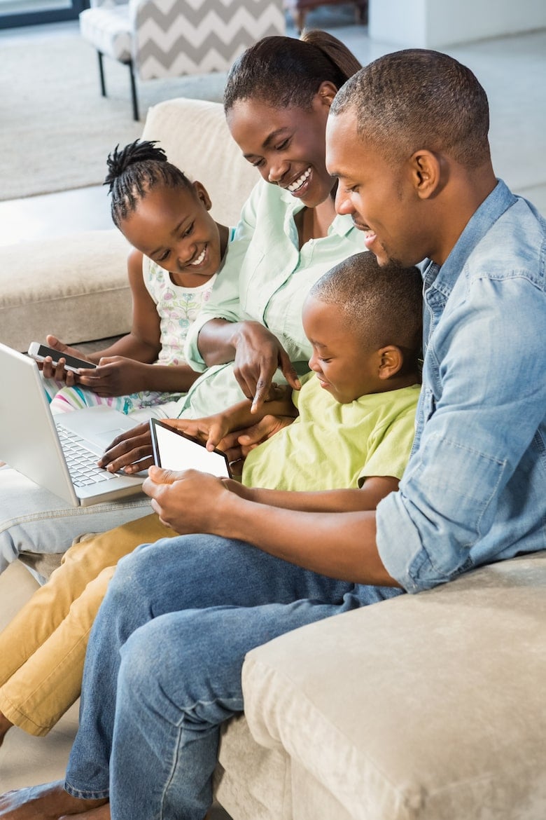 Happy family using technology together in living room