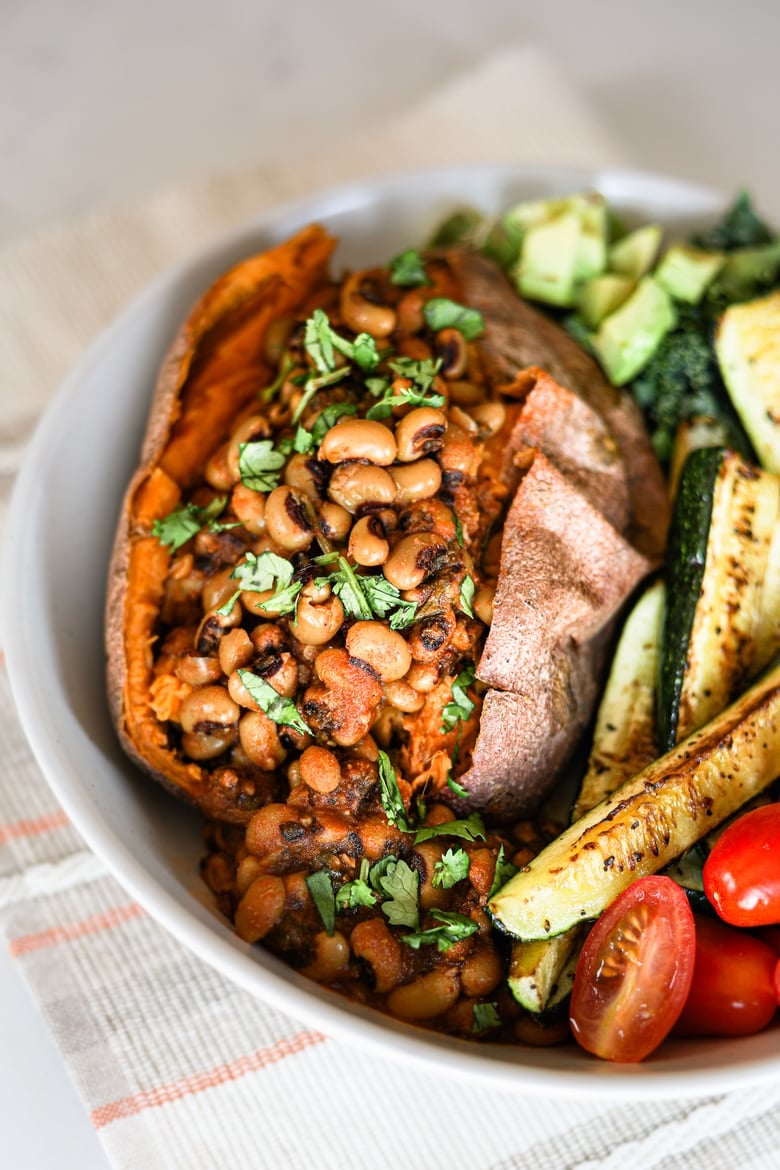 vegan black eyed peas recipe stuffed in a sweet potato with colourful vegetables in a bowl