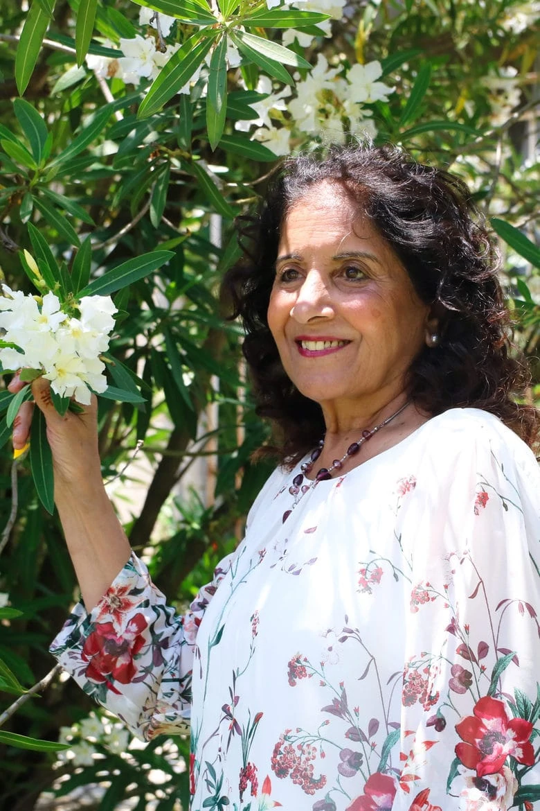 a woman standing next to a tree holding it's flowering branch - outdoors on Mother's Day 2020