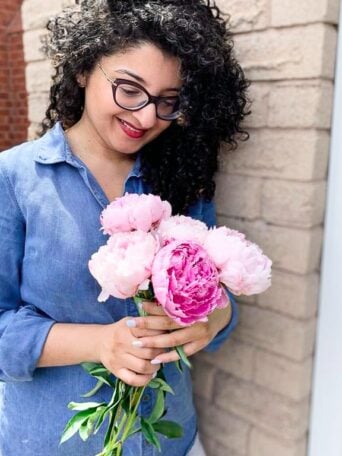 a lady standing with a bunch of pink peonies to celebrate Mother's Day 2020
