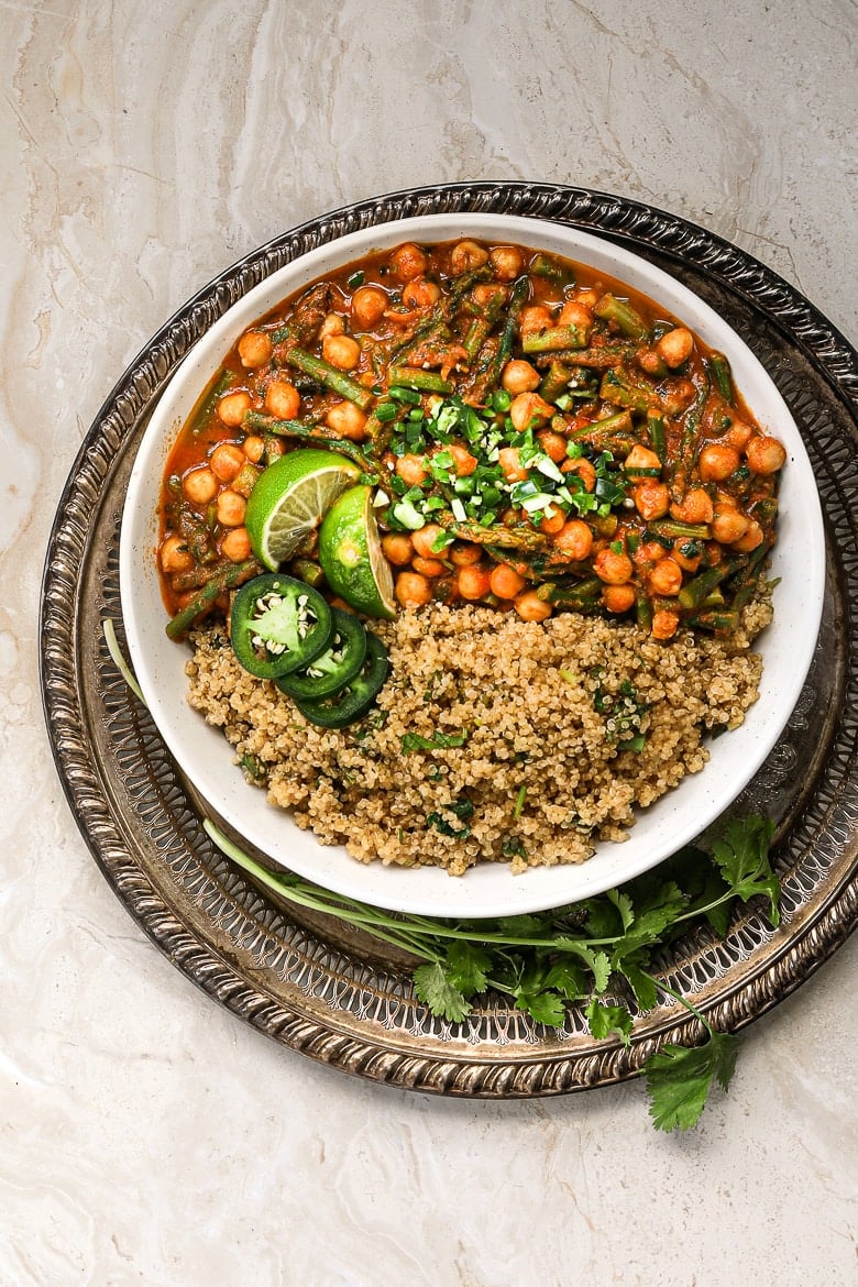 bowl of tikka masala with quinoa and lime and chillies on top in a gold tray - flatlay