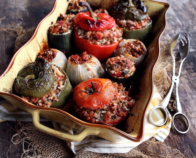 Baking dish filled with BBQ vegetables: pepper, tomato and onion stuffed with grains and herbs