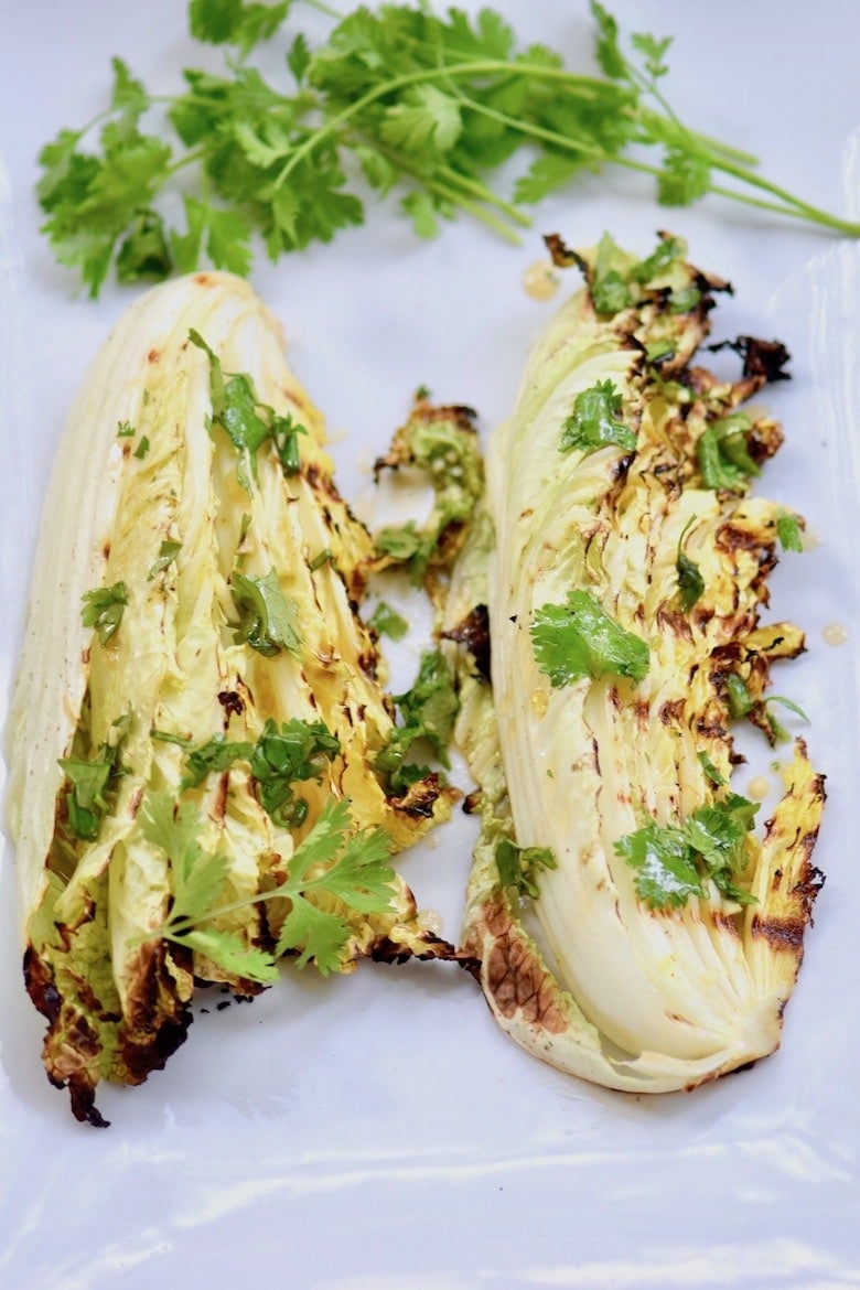 BBQ Chinese Cabbage on a white tray with a several sprigs of herbs