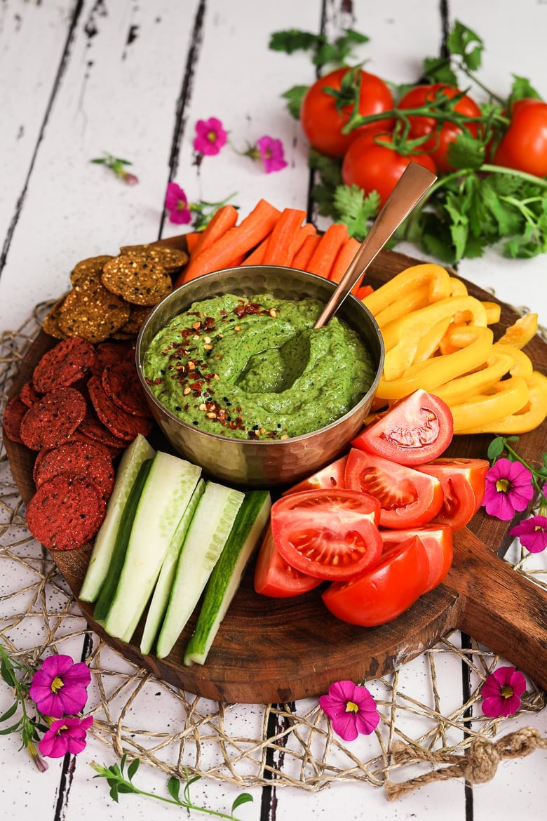 colourful platter of vegetables and crackers centred around a green avocado dip - perspective shot