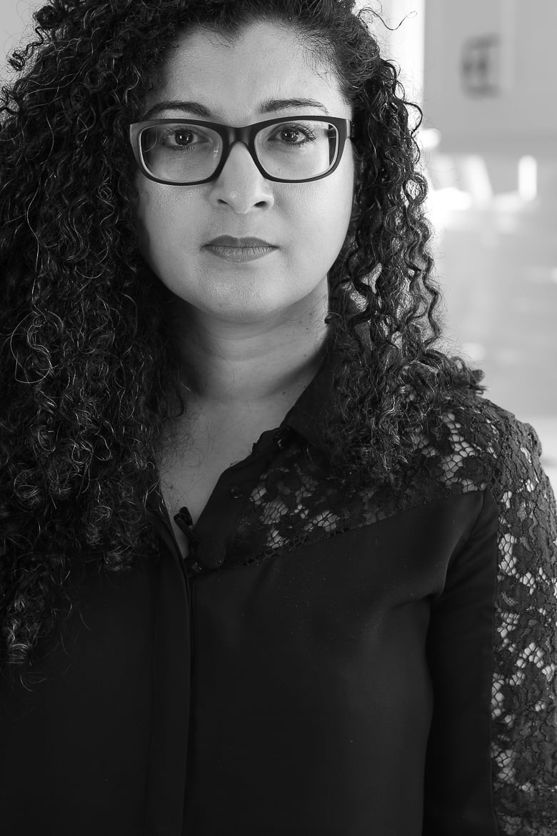 Photo of a woman with curly hair and glasses, black and white face on close up