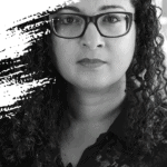 Photo of a woman with curly hair and glasses, black and white face on close up
