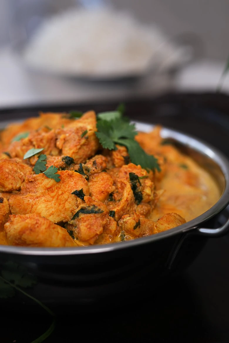 bowl of indian butter chicken garnished with cilantro - perspective shot