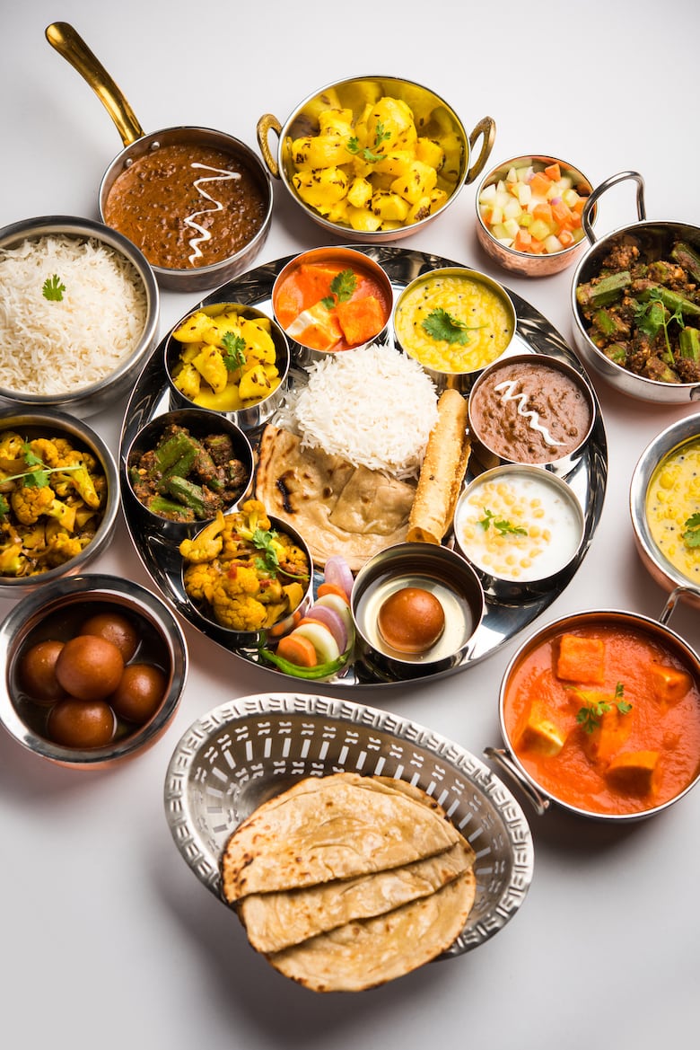 a selection of bowls of a variety of Indian dishes arranged in a circle