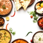a selection of plates and bowls of a variety of Indian dishes: naan, daals, curries and pickle