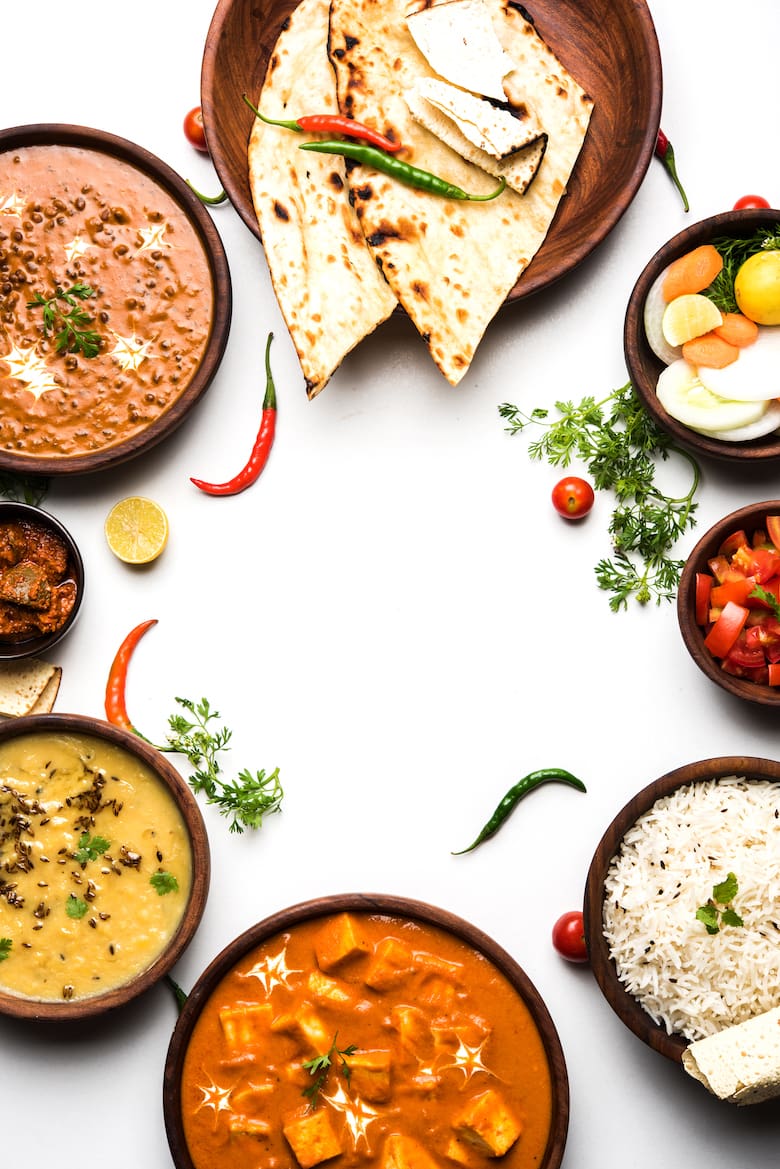 a selection of plates and bowls of a variety of Indian dishes: naan, daals, curries and pickle