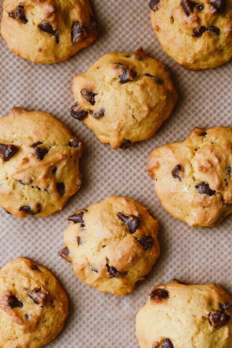 Homemade pumpkin cookies with chocolate chips made from cake mix on a baking sheet. Top view, flat lay.