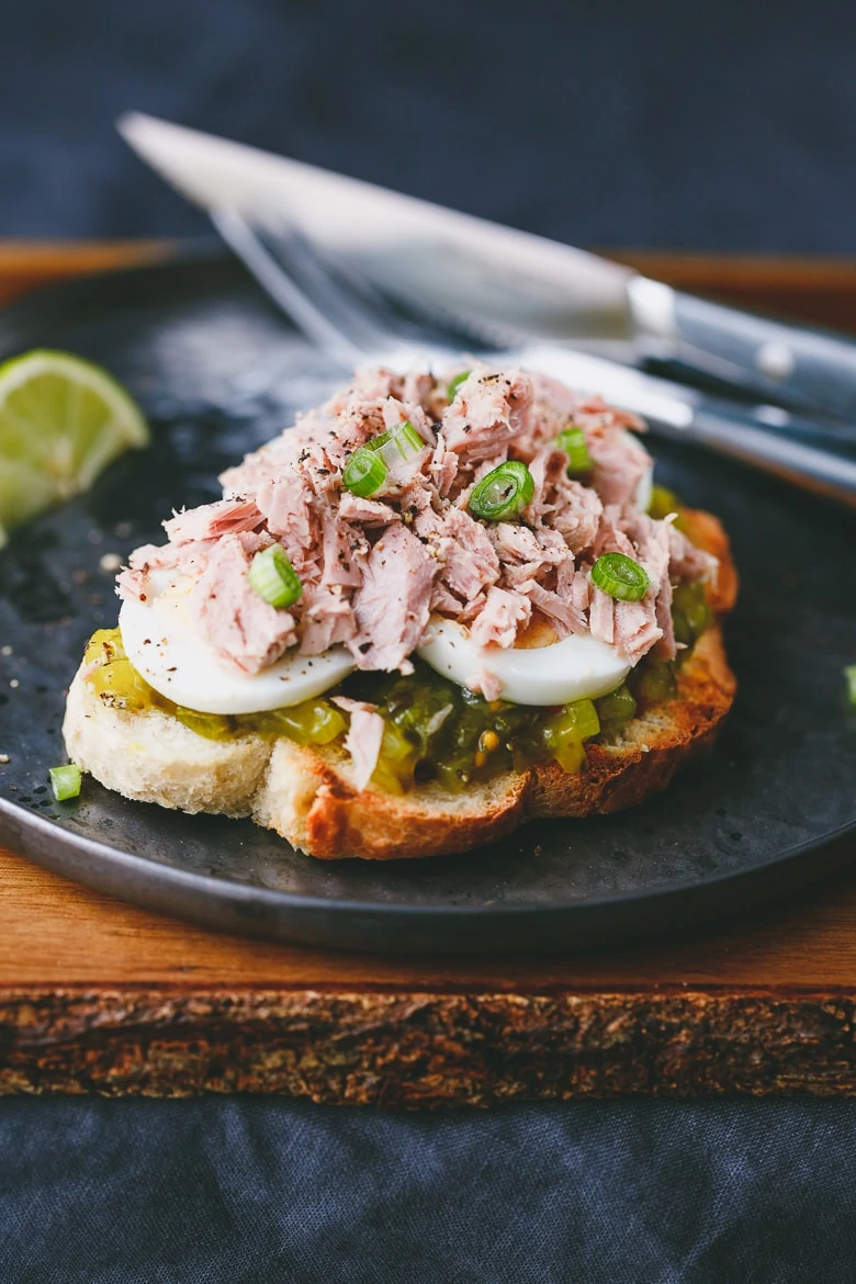 Open sandwich with canned tuna, egg and pickled cucumber dressing served with lime.