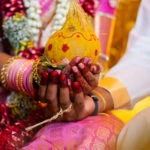 indian bride and groom on their wedding day holding a yellow coconut