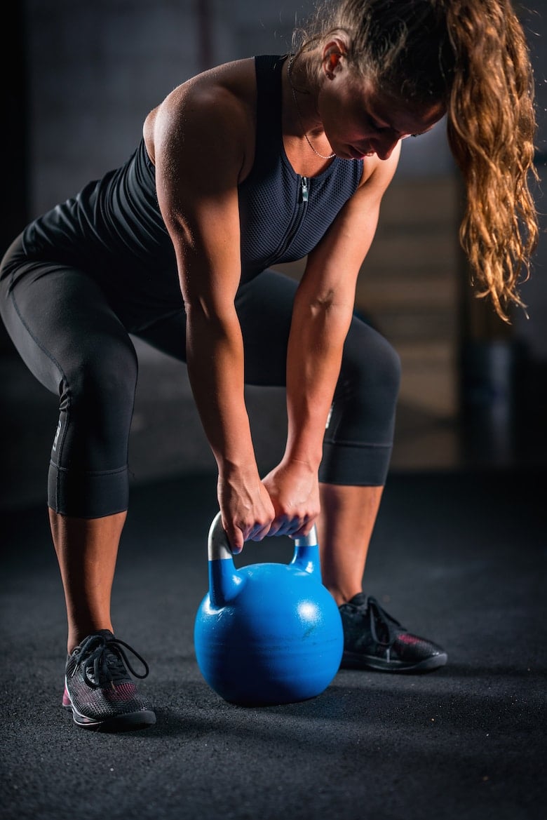 Woman athlete exercising with kettlebell indoors