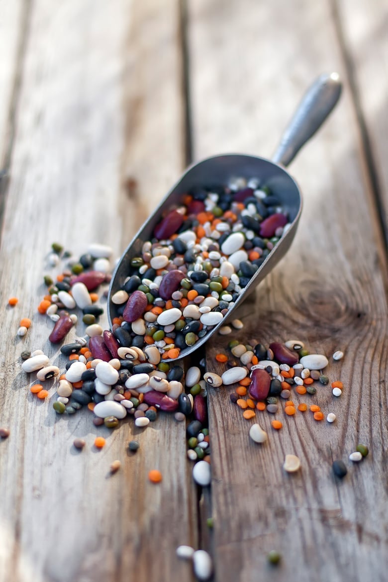 Mixed dry beans and lentil in scoop on old wood table