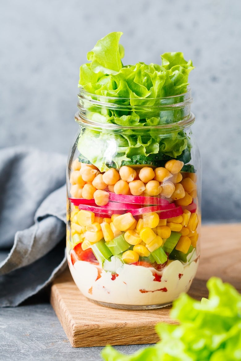 Single jar with layering vegan salad for healthy lunch with place for text. The concept of fitness and vegetarian food.