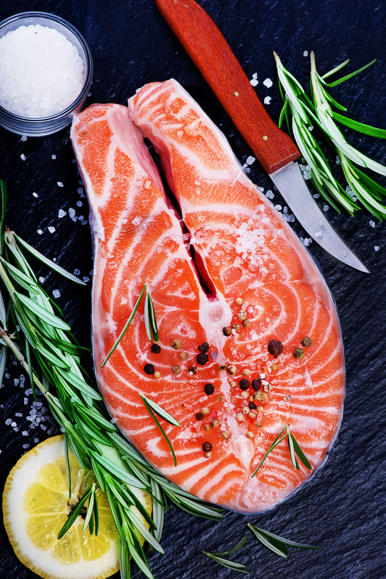 fresh salmon with rosemary on plate and on a table