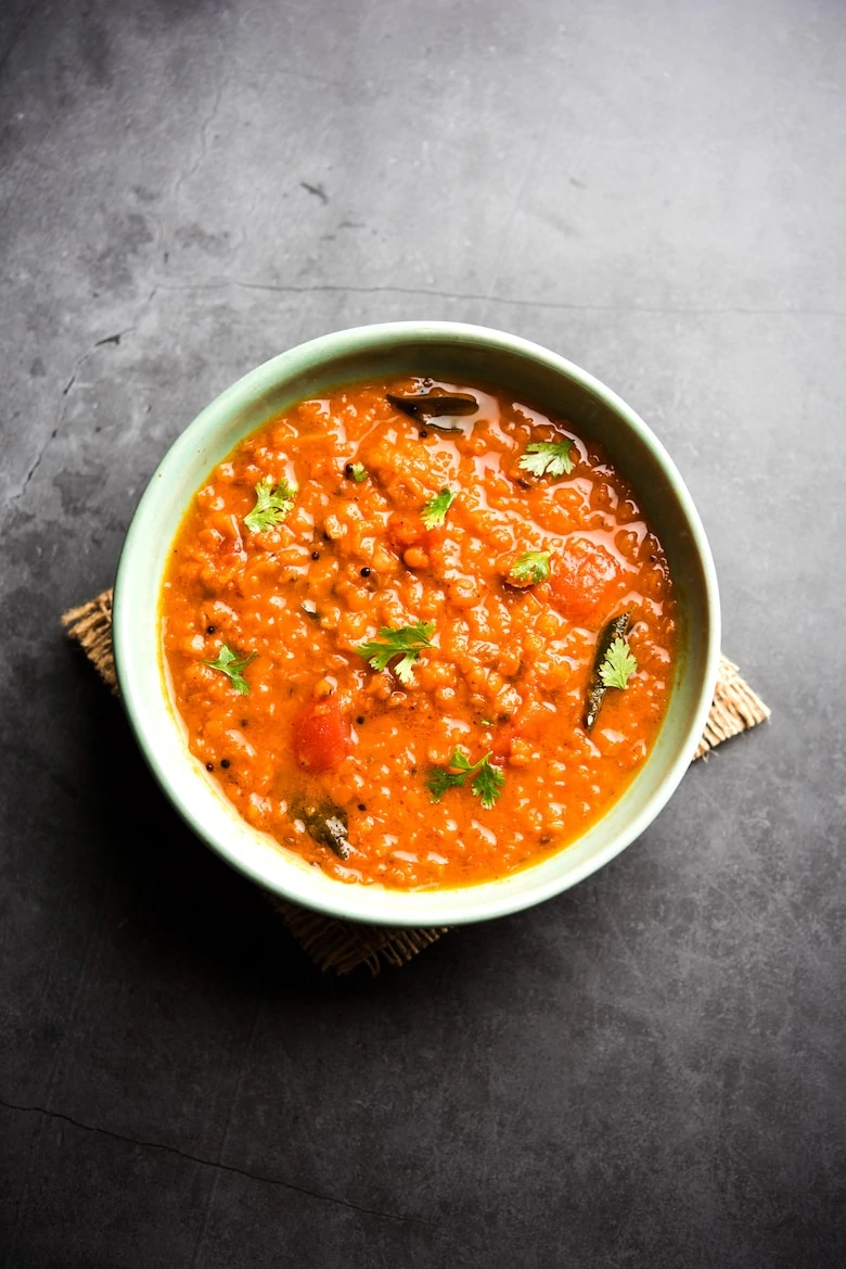 a bowl of red lentil curry against a charcoal backdrop