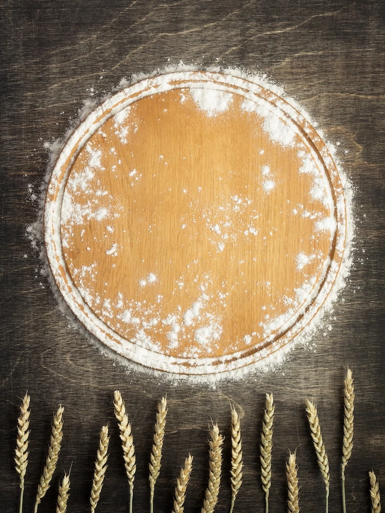 wheat flour and cutting board on wooden background, top view