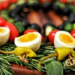 a low carb appetizer created as a edible holiday wreath, made with boiled eggs and vegetables on skewers on a bed of herbs