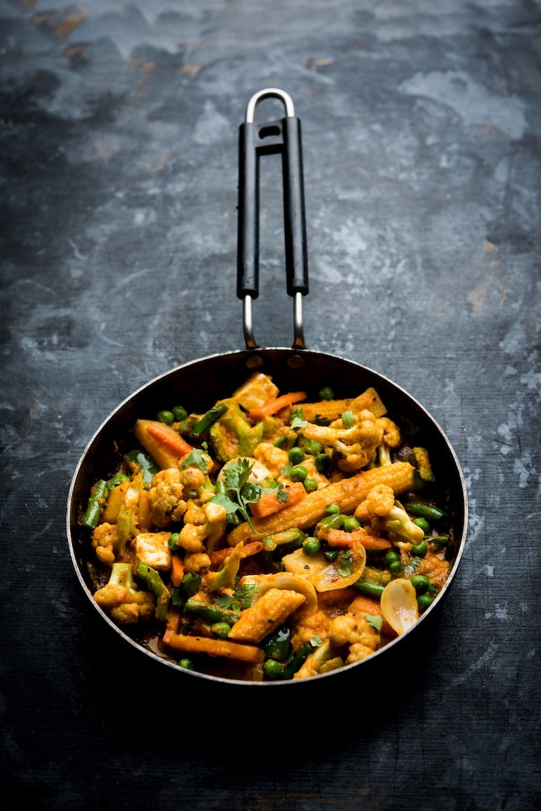 pan of Indian vegetable curry on a grey backdrop