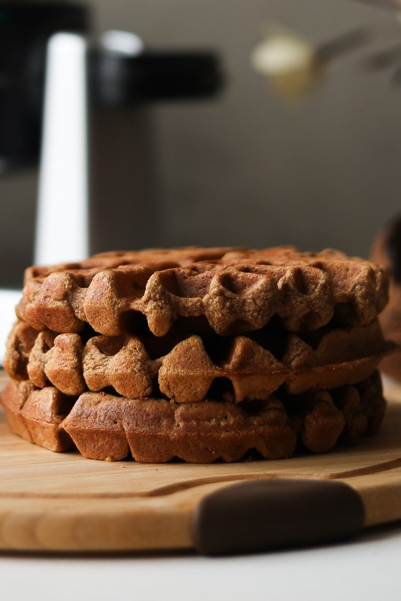 stack of brown vegan waffles on a round wooden board